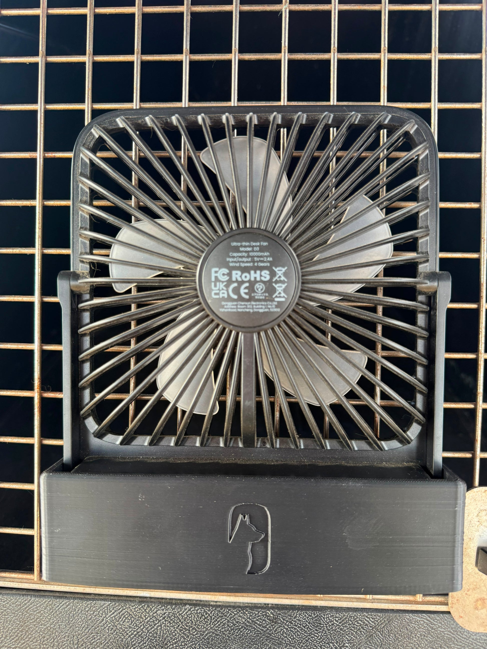 a sleek black mount to hold a warmco desk fan to the front of a dog crate