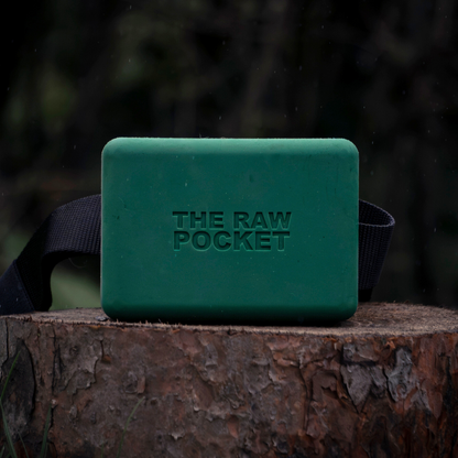 A green silicone treat pouch The Raw Pocket shown on a stump with a belt.